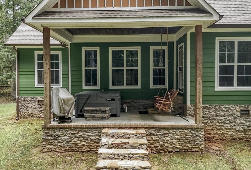 Covered front porch featuring a stone foundation, wood-finish columns, and a concrete surface