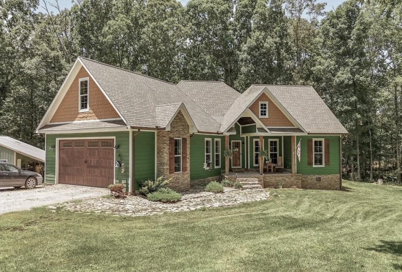 Craftsman-style home featuring a covered front porch with stone accents, a multi-pane front door, and a wood-finish garage door