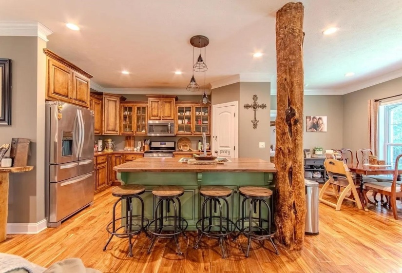 Spacious kitchen featuring wood-finish flooring, a central island with seating, stainless steel appliances, and wood cabinetry