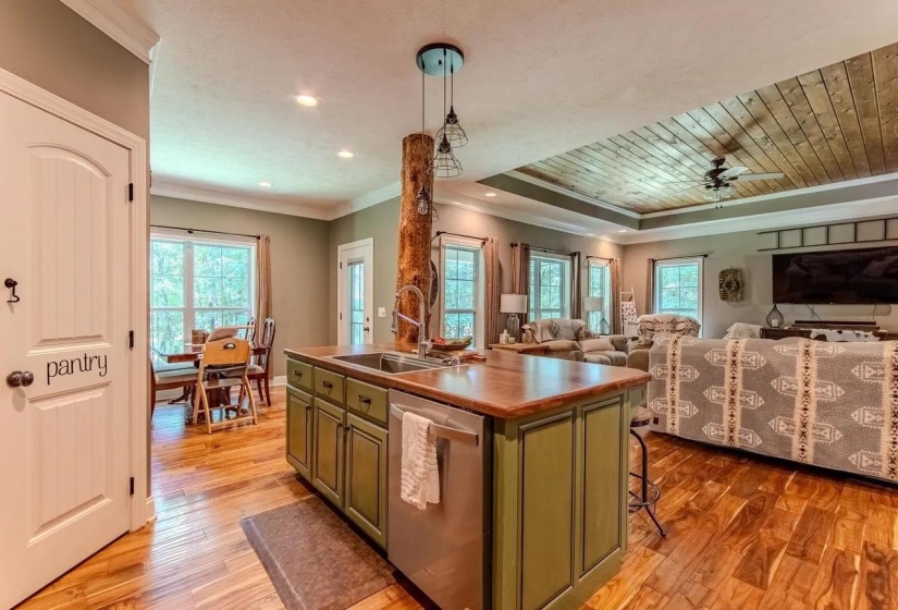 Kitchen island with a double basin sink, stainless steel dishwasher, and a rustic wood accent column
