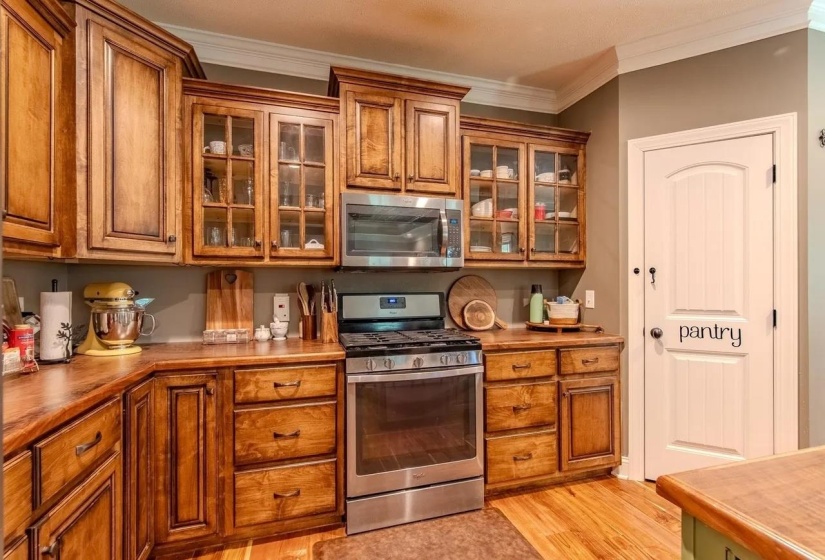 Kitchen featuring extensive wood cabinetry, wood-finish countertops, and stainless steel appliances