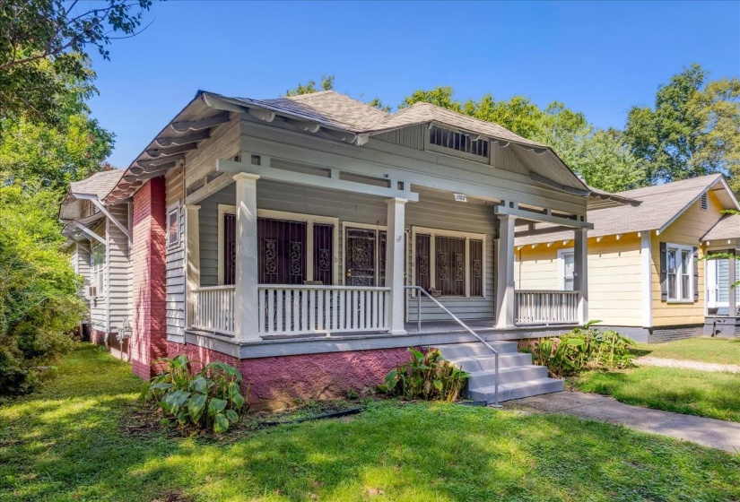 View of front of house with roof with shingles, covered porch, and a front lawn