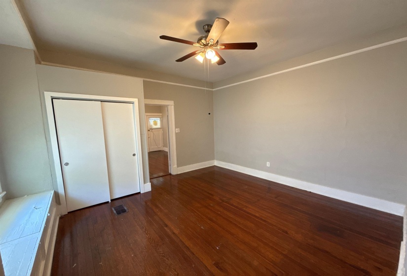 Unfurnished bedroom featuring dark wood finished floors, a closet, and ceiling fan
