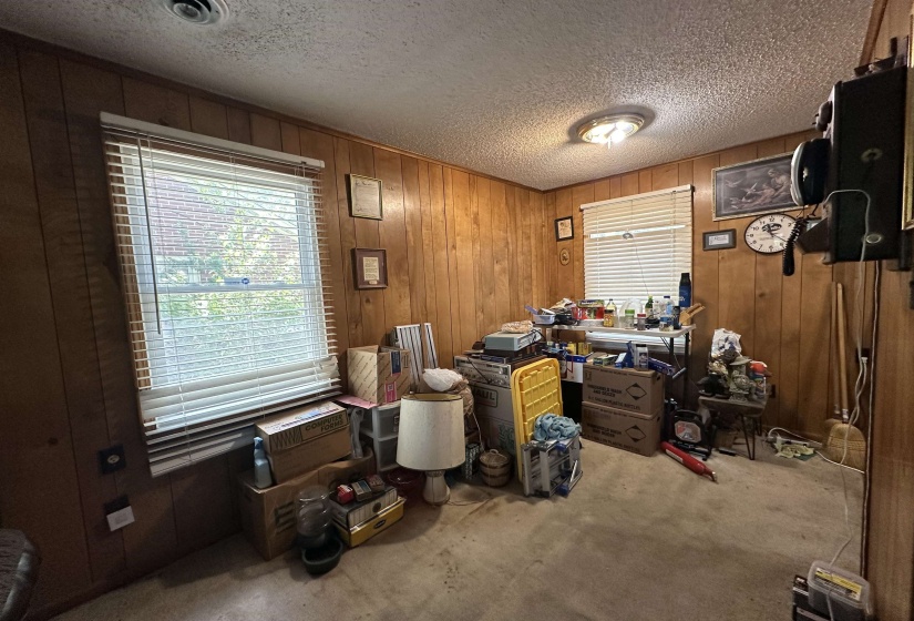 Paneled interior room featuring a window with blinds, carpeted flooring, and a ceiling-mounted light fixture