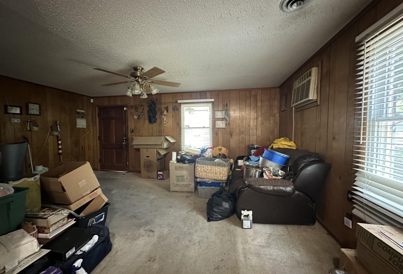 Wood-paneled room featuring white textured ceilings and light-colored carpeting