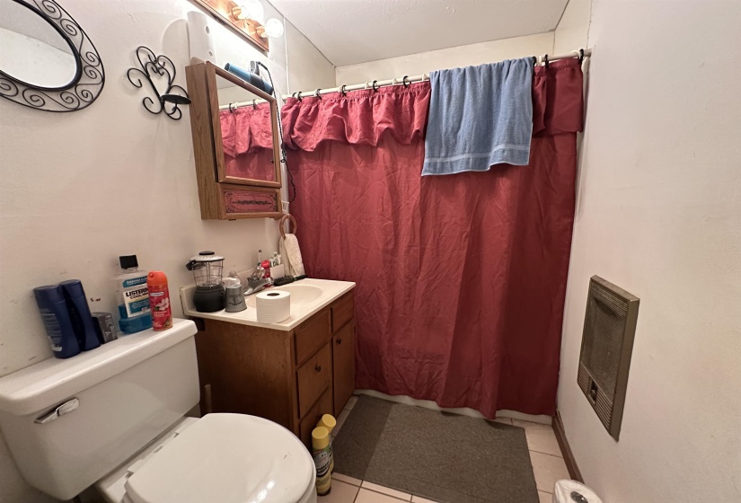 Bathroom featuring a white toilet, wood-finish vanity with an integrated sink, and a mirrored medicine cabinet
