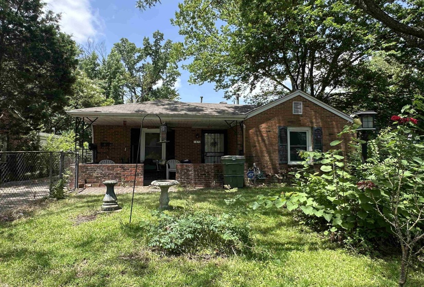 Brick facade home with a covered front porch featuring wrought iron supports and a low brick wall