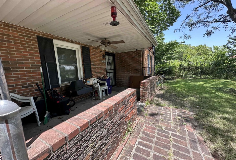 Brick exterior featuring a covered porch with a ceiling fan, a security door, and exterior shutters