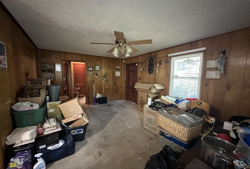 Room with wood paneling, a textured ceiling, and a ceiling fan with integrated lighting