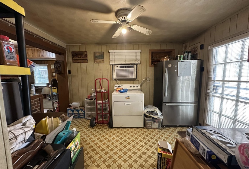 Utility area featuring paneling walls, geometric pattern flooring, a ceiling fan with integrated lighting, and a window with blinds