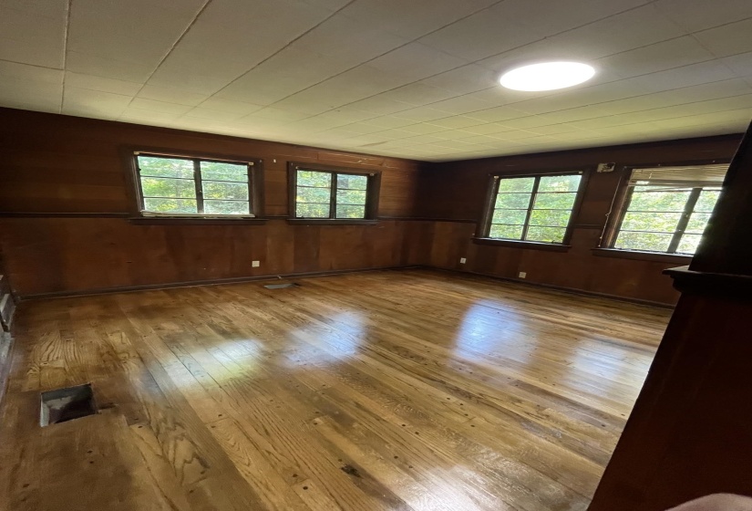 Wood-finish flooring accentuates this room featuring paneled walls, multiple windows, and a ceiling-mounted light fixture