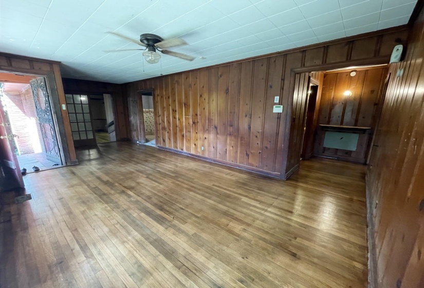 Wood-paneled room featuring wood-finish flooring, a ceiling fan, and multiple doorways