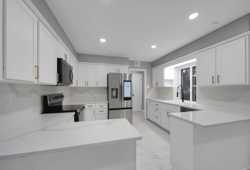 Kitchen featuring a peninsula, stainless steel refrigerator with ice dispenser, electric range oven, white cabinetry, and recessed lighting