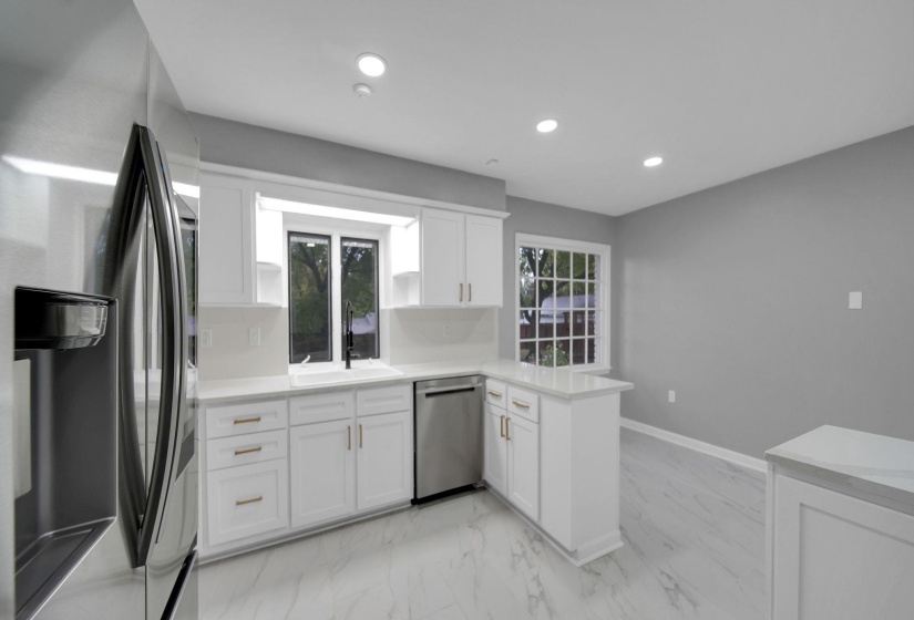 Kitchen featuring stainless steel appliances, a peninsula, white cabinets, light marble finish floors, and recessed lighting