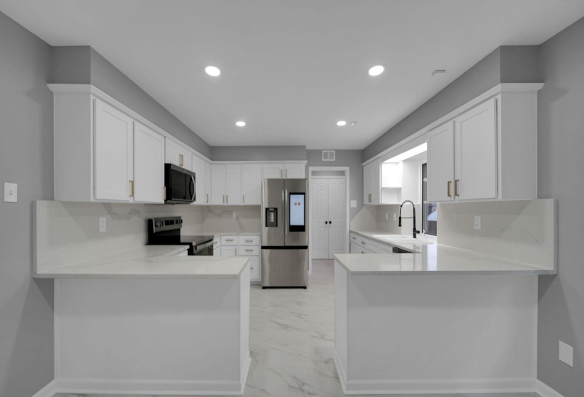 Kitchen with a peninsula, appliances with stainless steel finishes, recessed lighting, and white cabinetry