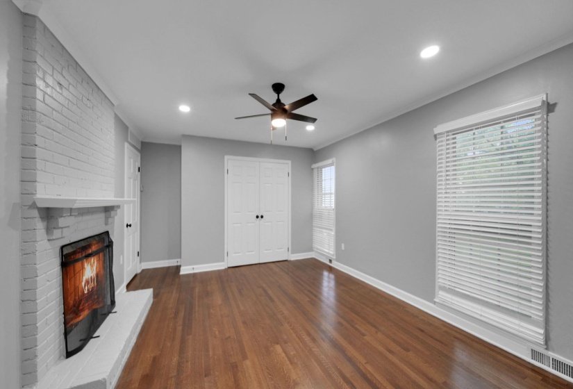 Unfurnished living room with dark wood-style flooring, a brick fireplace, ceiling fan, and recessed lighting