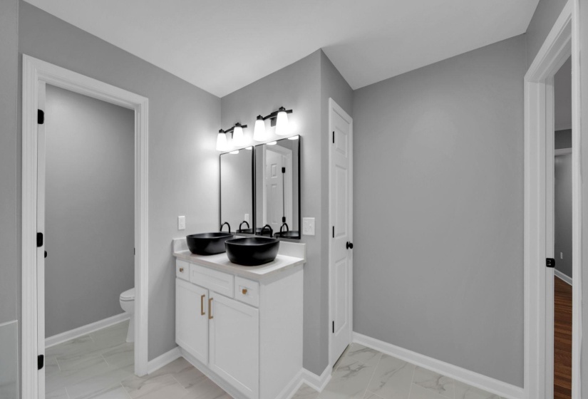 Full bath featuring light marble finish flooring and double vanity