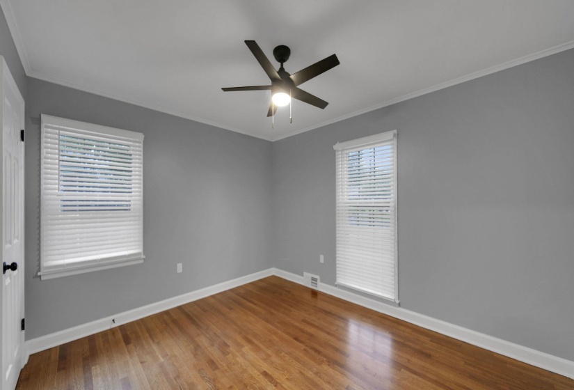 Spare room with crown molding, wood finished floors, and a ceiling fan
