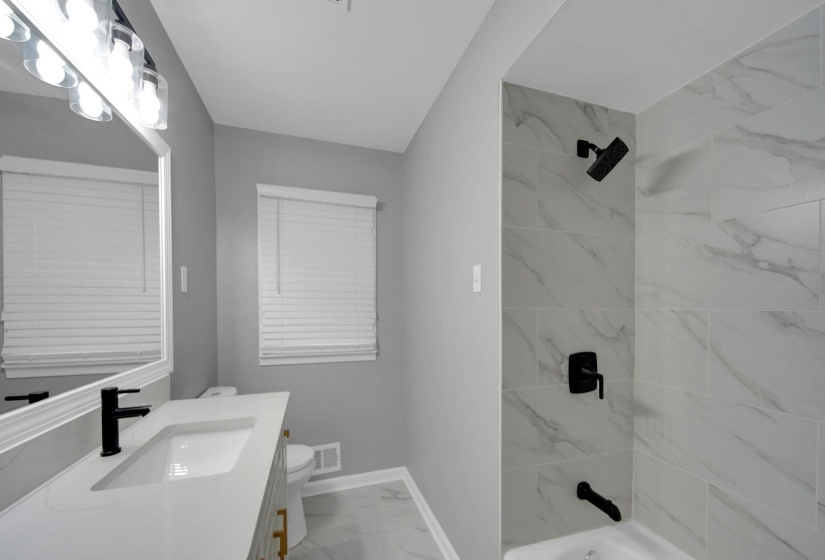 Full bath with light marble finish floors, shower / bathtub combination, and vanity