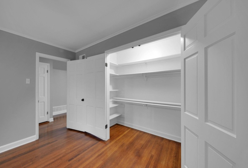 Unfurnished bedroom with dark wood finished floors, ornamental molding, and a walk in closet
