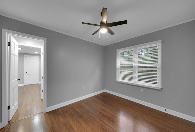 Empty room with crown molding, dark wood-type flooring, and a ceiling fan