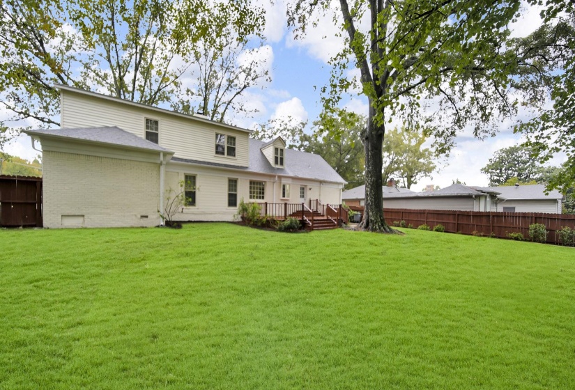 Rear view of house featuring a fenced backyard, brick siding, a wooden deck, and crawl space