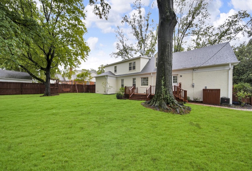 Rear view of house featuring a fenced backyard, a shingled roof, a wooden deck, and brick siding