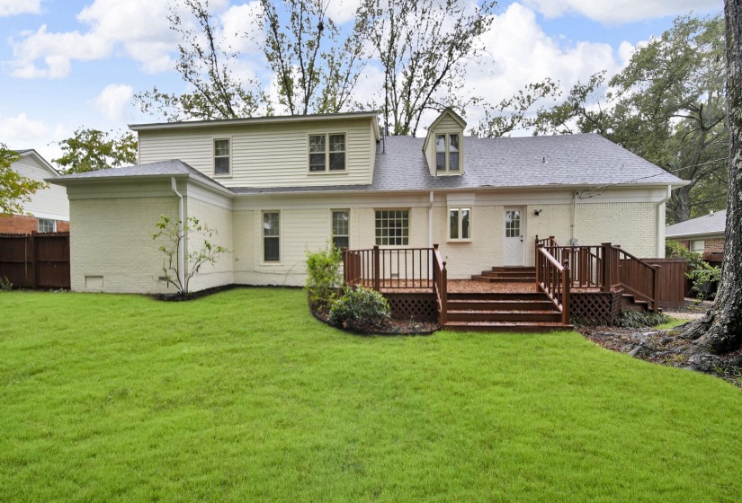 Rear view of property featuring brick siding, a deck, and roof with shingles