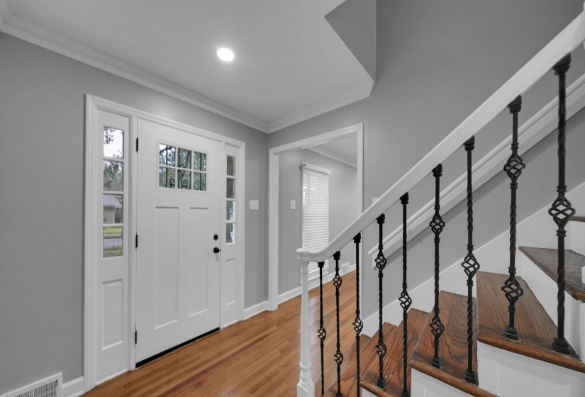 Foyer entrance featuring ornamental molding, stairs, and wood finished floors