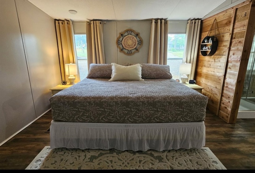 Spacious bedroom featuring wood-finish flooring and multiple windows
