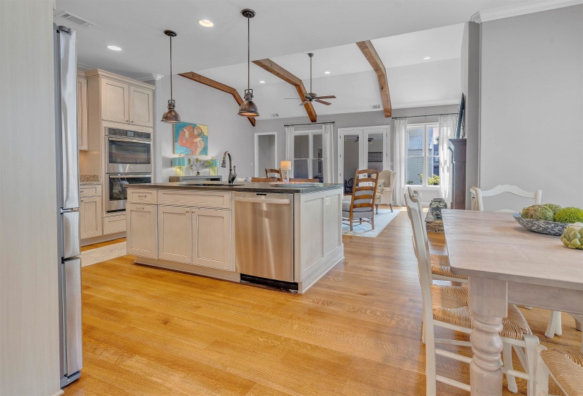 Gourmet kitchen featuring a central island with integrated sink, stainless steel appliances, light-toned cabinetry, and wood-finish flooring