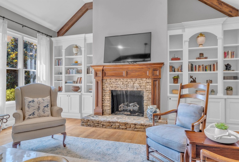 Stone-faced fireplace with a carved wood mantel, flanked by built-in white cabinetry and shelving