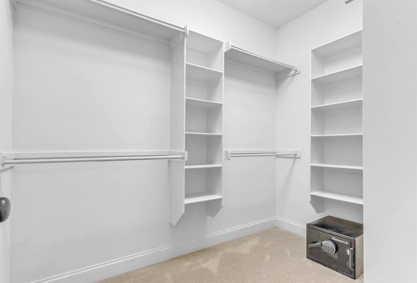 Walk-in closet featuring white wall paint, light-toned carpeting, built-in shelving, and multiple clothing rods