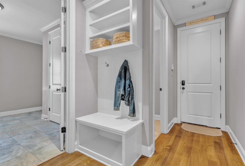 Built-in white storage bench with open shelving and coat hooks