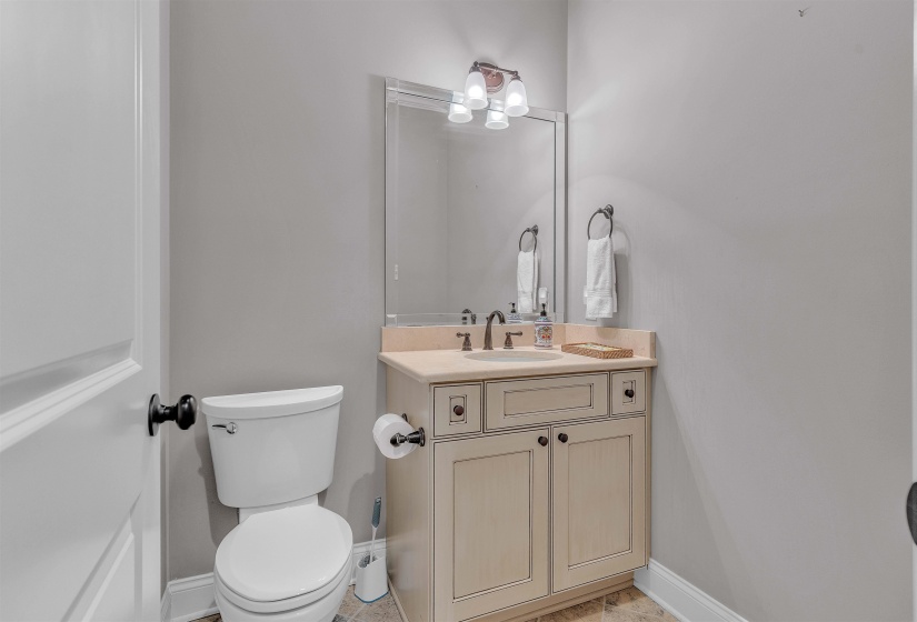 Powder room featuring a single vanity with a cream-colored cabinet, integrated sink, and bronze-finish faucet