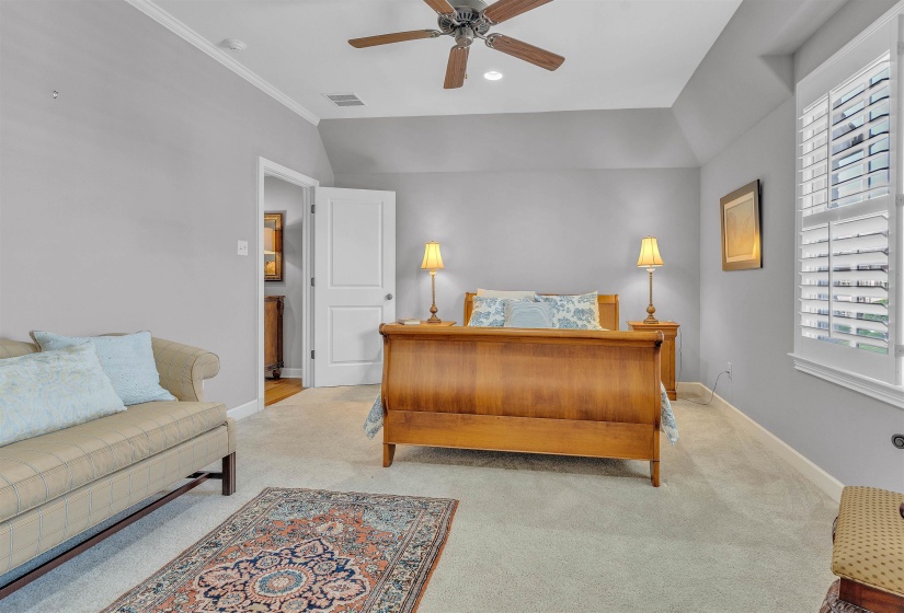 Spacious room featuring vaulted ceilings, light gray wall tones, plush carpeting, and a ceiling fan