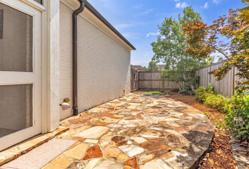 Flagstone patio with a privacy fence, mature trees, and landscaping