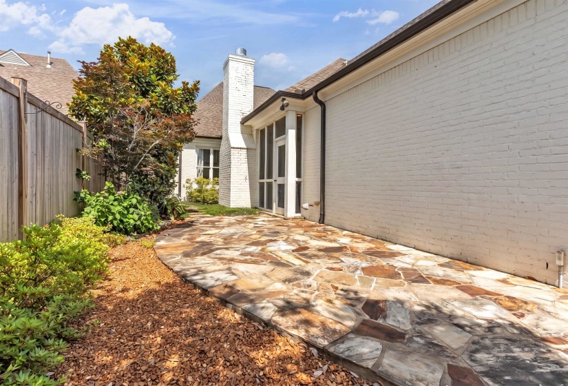 Flagstone patio with a white brick exterior and a privacy fence