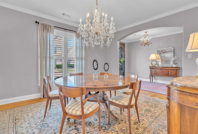 Dining area featuring a prominent crystal chandelier, wood-finish flooring, and white crown molding