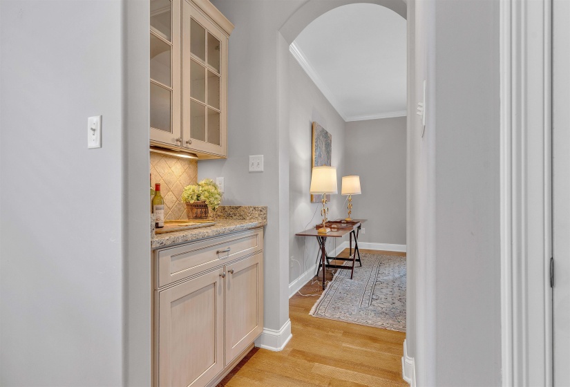 Built-in wet bar with glass-front upper cabinetry, granite countertop, and tiled backsplash