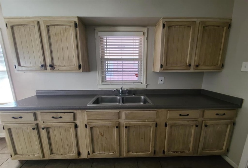 Kitchen featuring natural wood-finish cabinetry, a dual basin stainless steel sink, and dark countertops