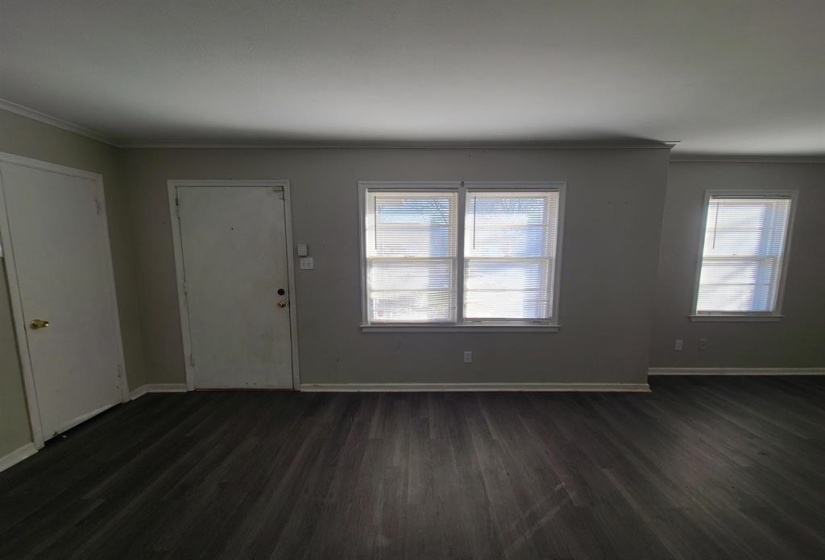Spacious interior featuring dark wood-finish flooring, light grey wall paint, white trim, and multiple windows