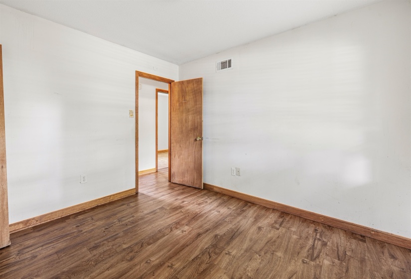 Room featuring wood-finish flooring, white painted walls, and light wood trim