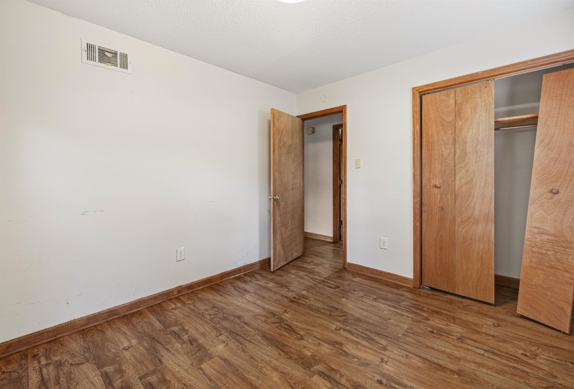 Room featuring wood-finish flooring, white walls, and wood-finish trim