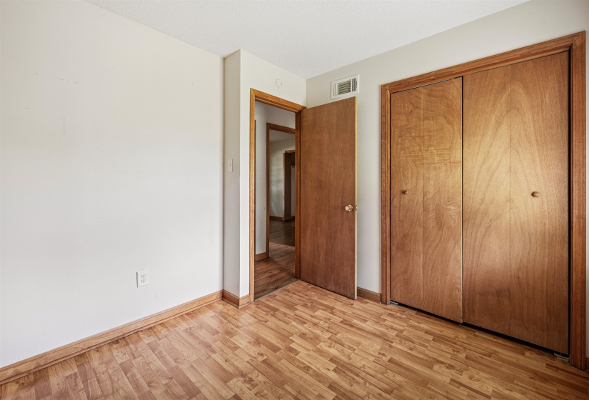 Room featuring wood-finish flooring, a bi-fold closet with wood doors, and an open doorway with wood trim