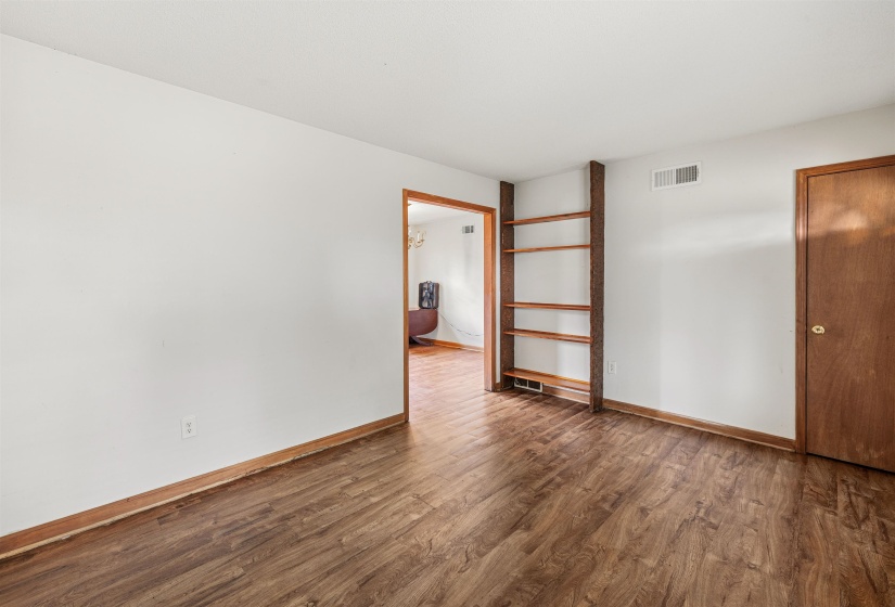 Bright interior room featuring wood-finish flooring, white walls, and a built-in shelving unit
