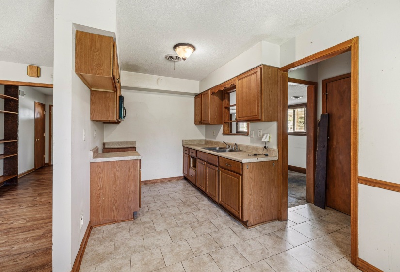 Kitchen featuring wood cabinetry, laminate countertops, and neutral tile flooring