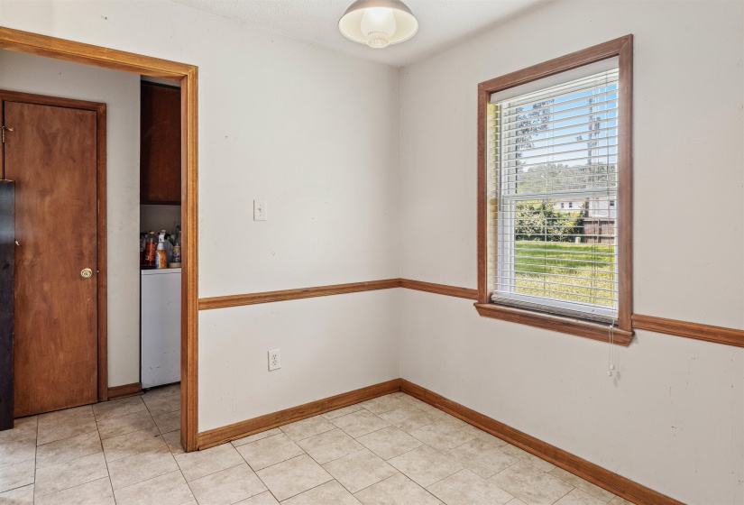 Room featuring a single window with blinds and wood-finish trim, ceramic tile flooring, and light-colored walls with wood-finish chair rail molding