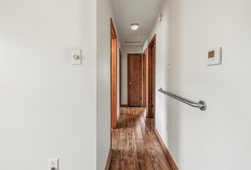 Hallway featuring wood-finish flooring, white walls, and wood-paneled doors