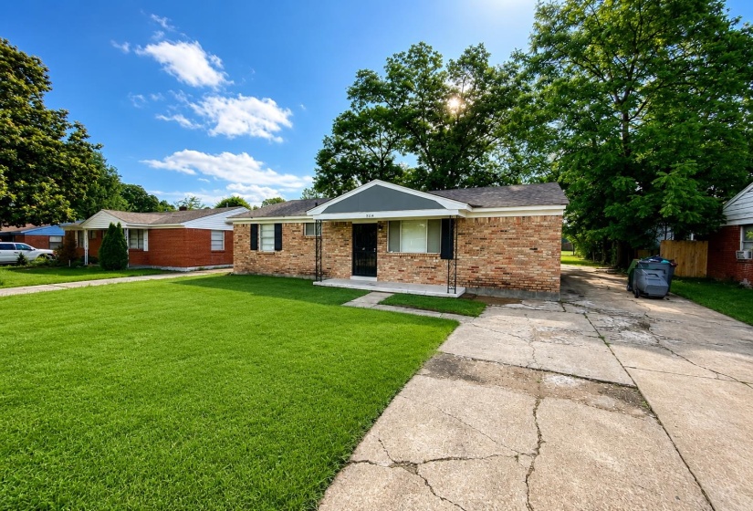 Brick ranch-style home featuring a covered entry, decorative window shutters, and a dark asphalt shingle roof